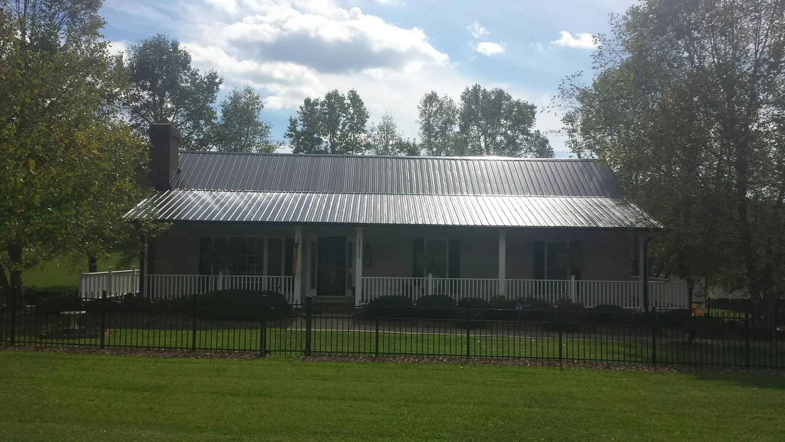 Gray metal roof on a brick ranch with a full width front porch — Gutter Guard Installation work by our crew in Philo